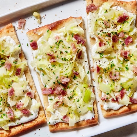 Crispy Sheet-Pan Flammkuchen Style Flatbread, featuring bacon, leeks, and bubbly crème fraîche topping.