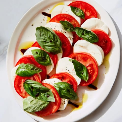 Enjoy juicy Sliced Tomatoes and Mozzarella Rounds, drizzled with olive oil, perfect for summer.