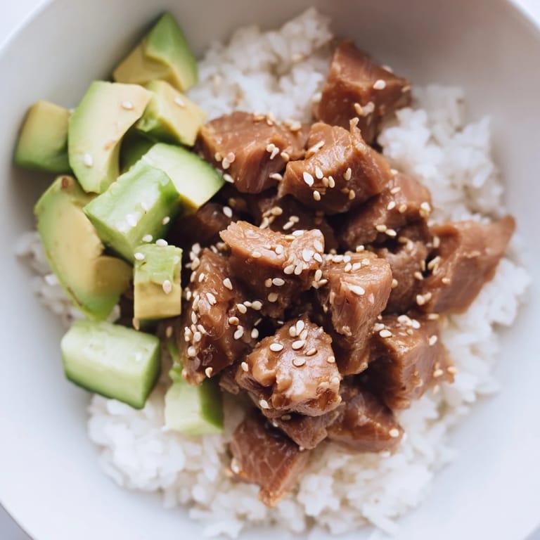 Farbenfroher Tuna Avocado Rice Bowl mit gestapelten Zutaten auf warmem Reis, fertig für eine gesunde Mahlzeit.